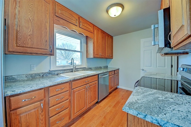 kitchen with brown cabinetry, baseboards, light wood finished floors, a sink, and stainless steel appliances