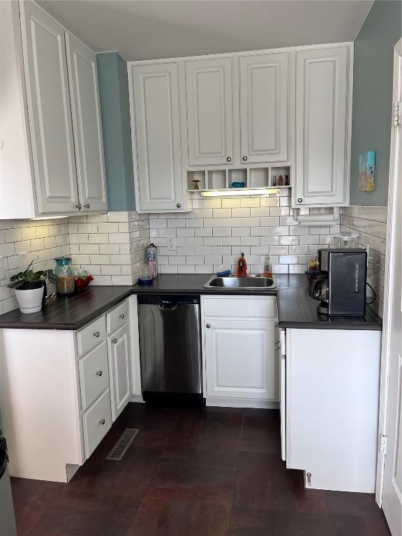 kitchen with stainless steel dishwasher, dark countertops, white cabinetry, and a sink