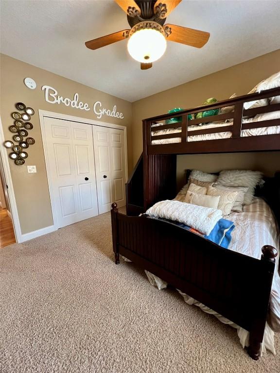 bedroom featuring a ceiling fan, carpet, a closet, and baseboards