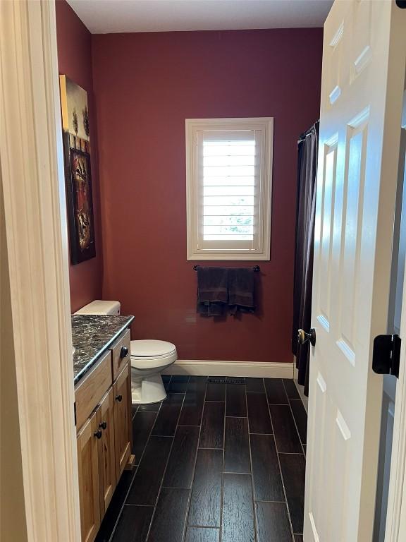 full bathroom with vanity, toilet, baseboards, and wood tiled floor