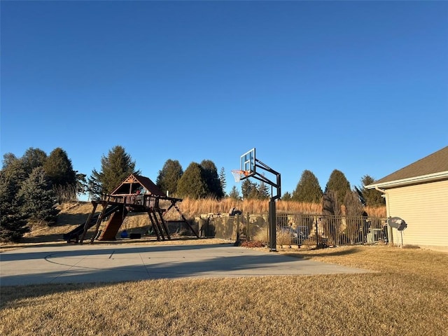 view of basketball court featuring a playground, fence, and basketball court