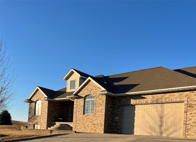 view of front facade with brick siding, driveway, and a garage