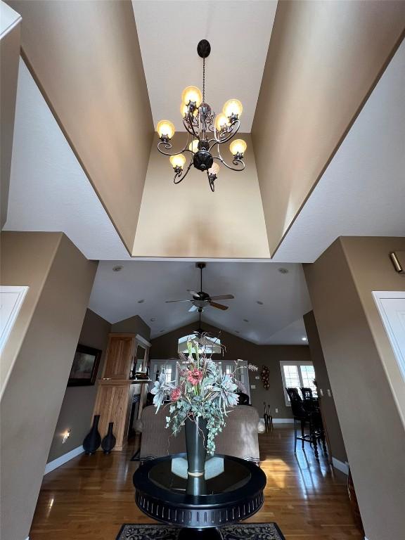 dining area with baseboards, high vaulted ceiling, wood finished floors, and ceiling fan with notable chandelier