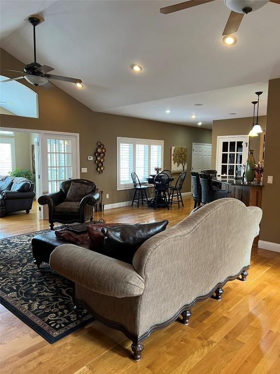 living room featuring baseboards, lofted ceiling, wood finished floors, and a ceiling fan