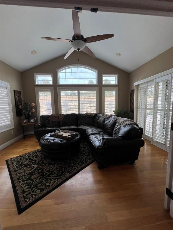 living area with a healthy amount of sunlight, wood finished floors, and vaulted ceiling