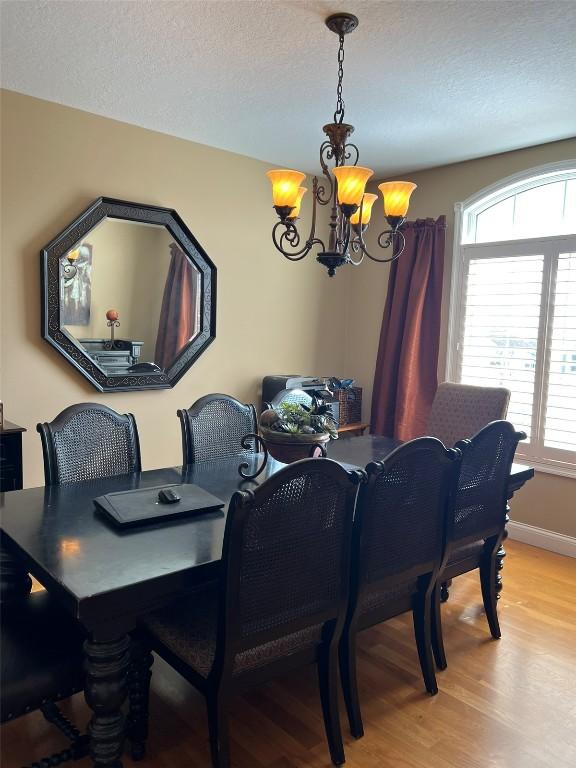 dining room with a textured ceiling, baseboards, an inviting chandelier, and wood finished floors