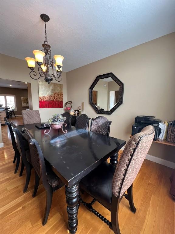 dining area with a chandelier, a textured ceiling, baseboards, and wood finished floors