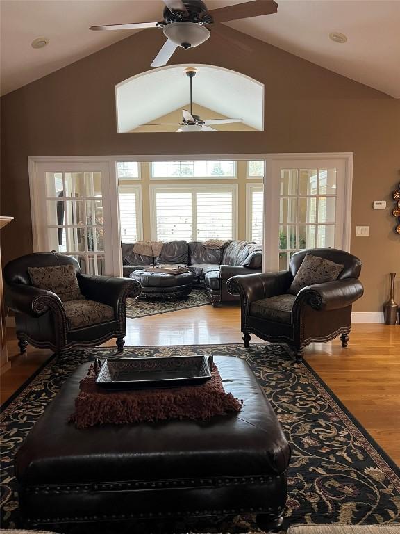 living room with baseboards, lofted ceiling, wood finished floors, and a ceiling fan