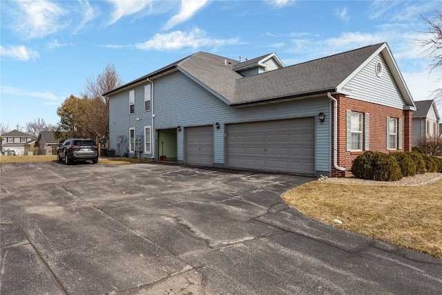 3260 Willowridge Rd Unit D, Marion, IA 52302 - view of home's exterior featuring an attached garage, central AC unit, brick siding, and asphalt driveway