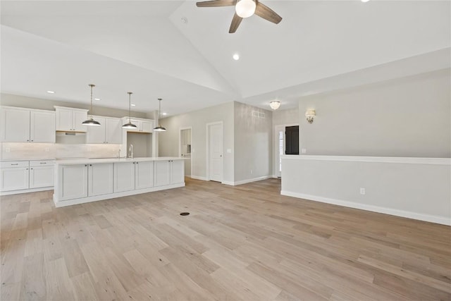 unfurnished living room featuring light wood-type flooring, baseboards, high vaulted ceiling, and a ceiling fan