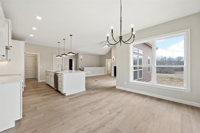 kitchen with open floor plan, light countertops, stainless steel dishwasher, white cabinets, and a sink