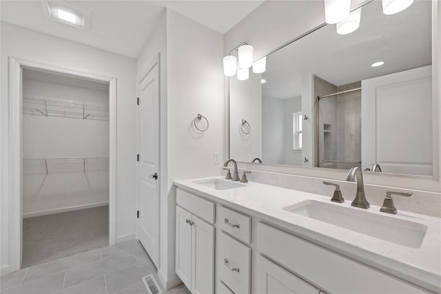 full bathroom with tile patterned flooring, double vanity, a stall shower, and a sink