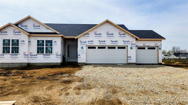 property in mid-construction featuring roof with shingles, driveway, and an attached garage