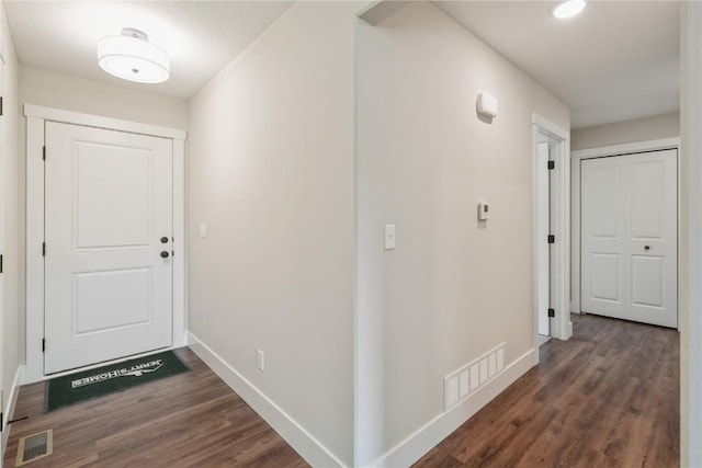 hall featuring wood finished floors, visible vents, and baseboards