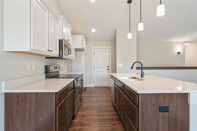 kitchen with a sink, light countertops, appliances with stainless steel finishes, white cabinetry, and a kitchen island with sink