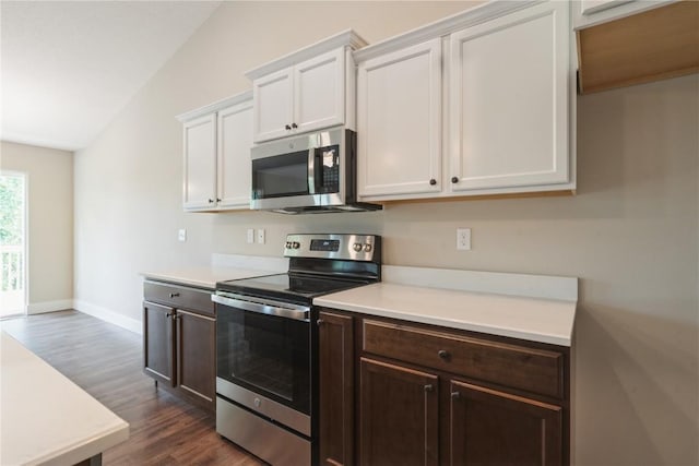 kitchen with dark wood finished floors, stainless steel appliances, light countertops, and vaulted ceiling