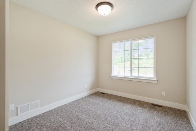 carpeted empty room featuring baseboards and visible vents