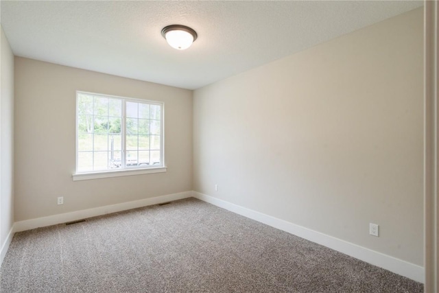 unfurnished room with carpet, visible vents, and baseboards