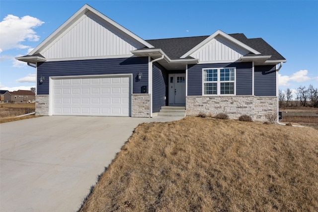 view of front of property with board and batten siding, concrete driveway, a garage, and stone siding