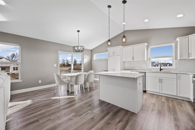 kitchen featuring tasteful backsplash, plenty of natural light, white cabinets, and vaulted ceiling