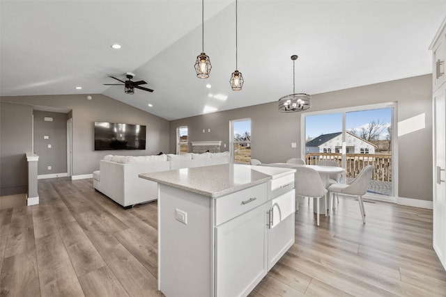 kitchen with light wood finished floors, white cabinets, a center island, and vaulted ceiling