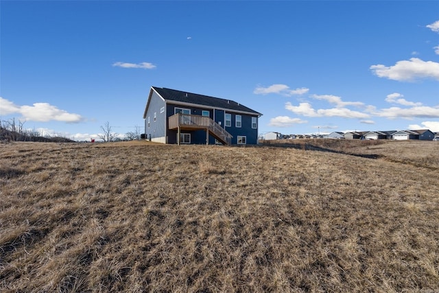 back of property featuring stairs and a deck