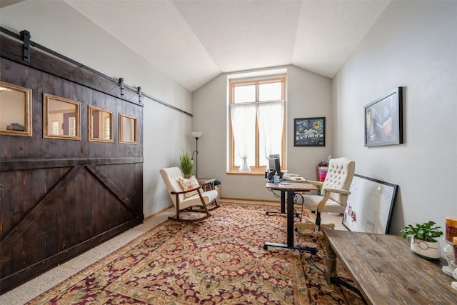 office area featuring a barn door, baseboards, lofted ceiling, and carpet floors