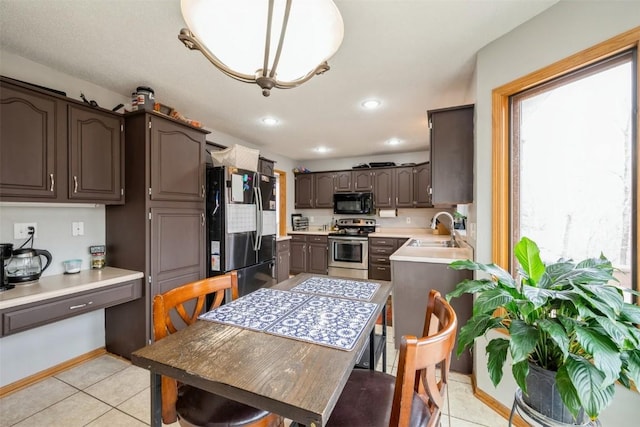 kitchen featuring fridge with ice dispenser, a sink, stainless steel range with electric cooktop, black microwave, and light countertops