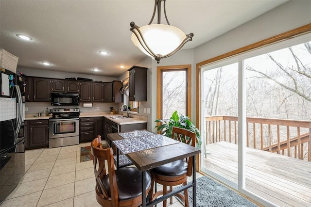 kitchen featuring a sink, black appliances, light tile patterned flooring, and light countertops