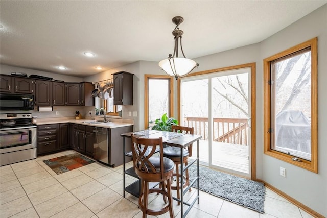 kitchen with dark brown cabinets, baseboards, light countertops, stainless steel appliances, and a sink