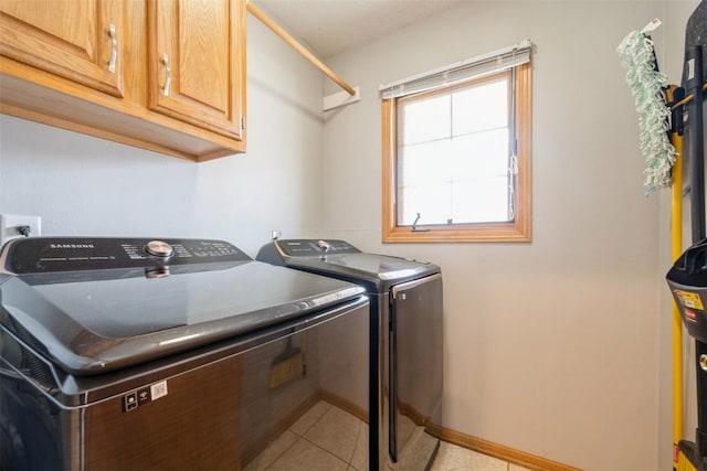 clothes washing area featuring cabinet space, light tile patterned floors, independent washer and dryer, and baseboards