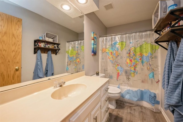 bathroom with visible vents, shower / bath combo with shower curtain, toilet, wood finished floors, and vanity