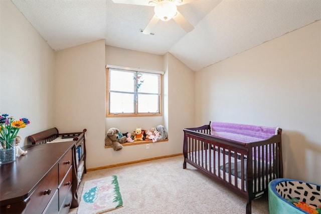 carpeted bedroom featuring baseboards, lofted ceiling, ceiling fan, a crib, and a textured ceiling