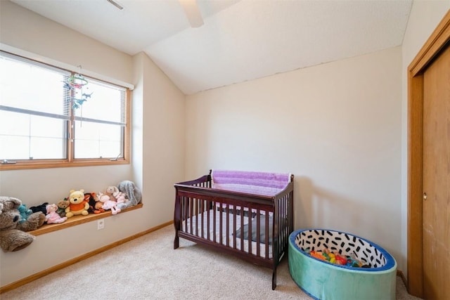 bedroom with a crib, a closet, carpet floors, baseboards, and vaulted ceiling