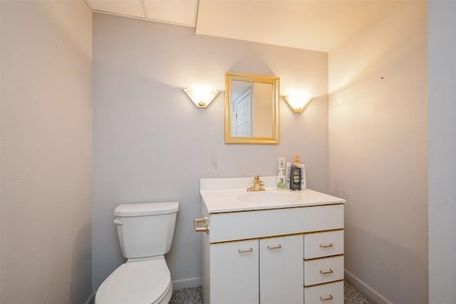 half bath with baseboards, toilet, and vanity