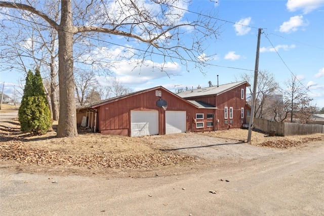 view of side of home featuring dirt driveway and fence