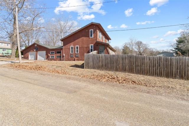 view of side of property featuring fence and a garage