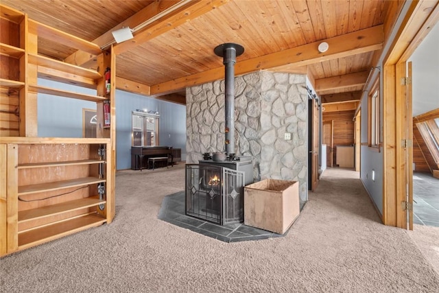 interior space with beamed ceiling, wood ceiling, a wood stove, and carpet floors