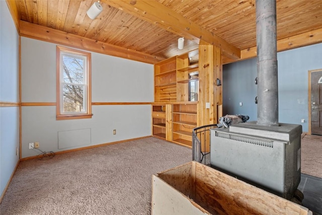 living area with beam ceiling, carpet flooring, wooden ceiling, and a wood stove