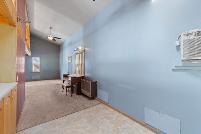 office space featuring a wall mounted air conditioner, high vaulted ceiling, a ceiling fan, radiator heating unit, and light colored carpet