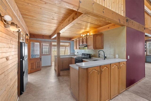 kitchen with a sink, freestanding refrigerator, range with gas cooktop, a peninsula, and wood ceiling