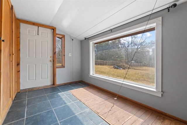 foyer featuring lofted ceiling and baseboards