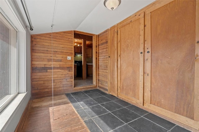 hallway featuring lofted ceiling and wood walls