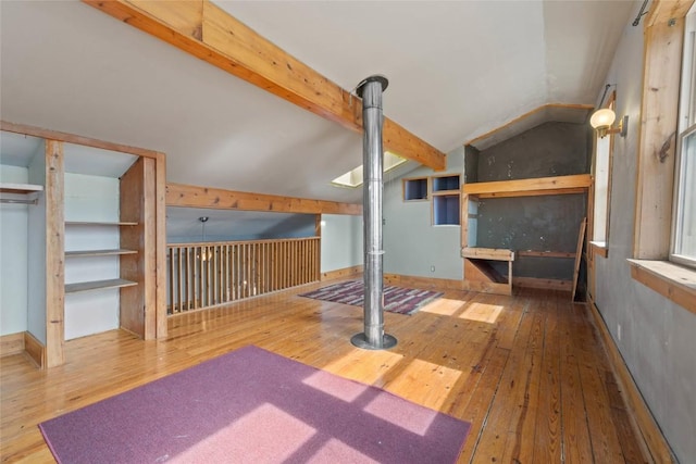 unfurnished bedroom with lofted ceiling with beams, baseboards, and wood-type flooring