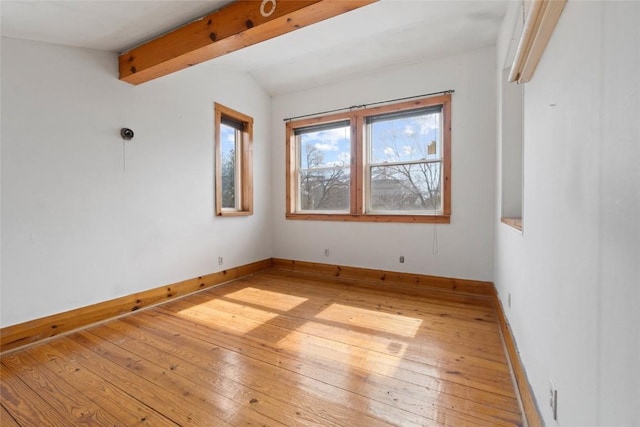 unfurnished room with baseboards, light wood-style flooring, and vaulted ceiling with beams