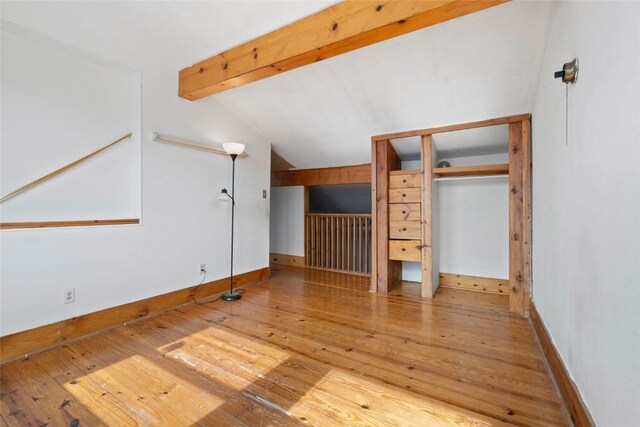 interior space with hardwood / wood-style floors, lofted ceiling with beams, and baseboards