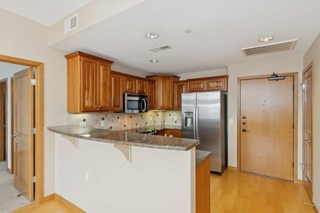 kitchen featuring a peninsula, a breakfast bar area, visible vents, and stainless steel appliances