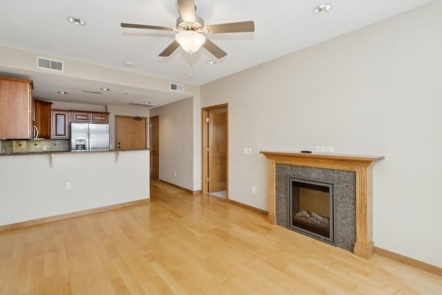 unfurnished living room featuring light wood finished floors, visible vents, and a fireplace