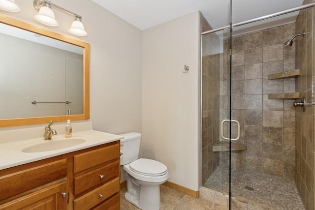 bathroom featuring tile patterned floors, toilet, a shower stall, baseboards, and vanity