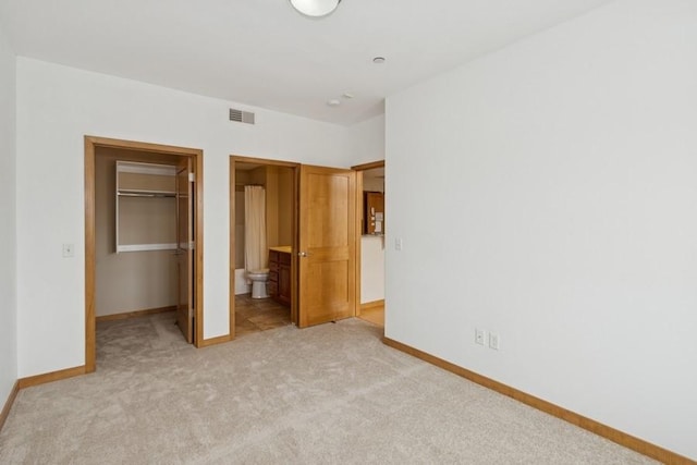 unfurnished bedroom featuring visible vents, baseboards, a spacious closet, a closet, and light colored carpet